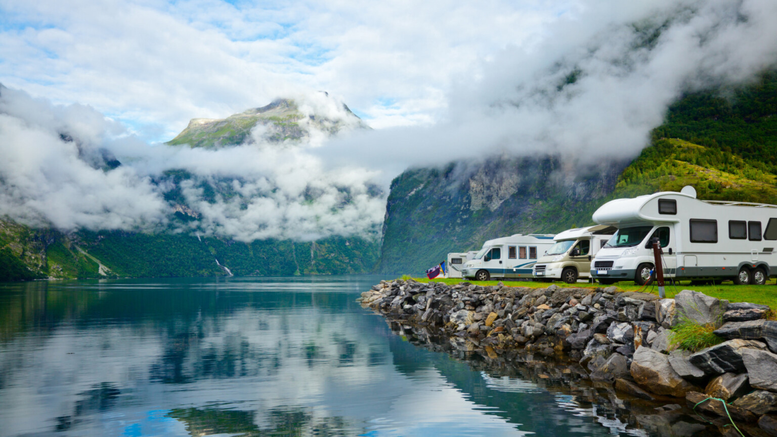 lago con fondo de montañas y autocaravanas aparcadas